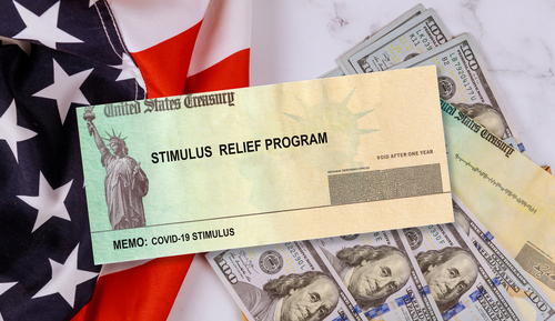 shutterstock_1693772764.jpg featured image Stimulus check on American flag with US dollars.