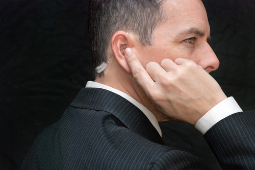 Man in suit with earpiece, looking serious.