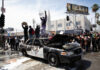 Protesters standing on damaged police car, holding signs.