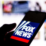 Phone displaying Fox News logo in a dark surrounding.