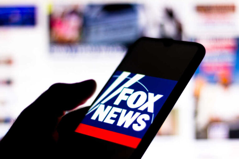 Phone displaying Fox News logo in a dark surrounding.