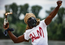Person in gas mask with Molotov cocktail, shirt.