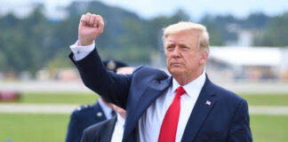 A man in a suit raises his fist outdoors.