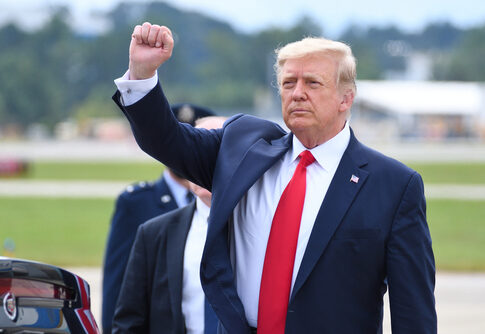 A man in a suit raises his fist outdoors.