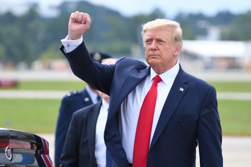 A man in a suit raises his fist outdoors.