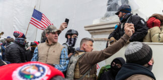 People at U.S. Capitol riot, holding flags and phones.