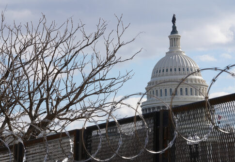 U.S. Capitol behind fence and barbed wire.