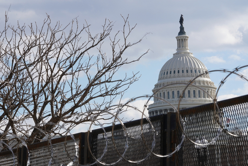 U.S. Capitol behind fence and barbed wire.