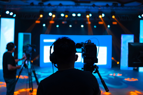 shutterstock_1910421457.jpg featured image Camera operators filming a brightly lit stage.