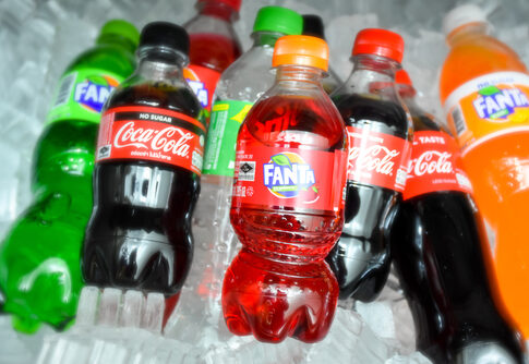 Assorted soda bottles including Coca-Cola and Fanta on ice.