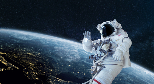 shutterstock_1936566580.jpg featured image Astronaut floating in space above Earth, waving.