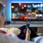 Person watching TV with bowl of popcorn.