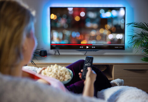 Person watching TV with bowl of popcorn.