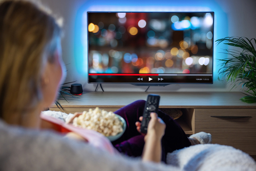 shutterstock_1966720738.jpg featured image Person watching TV with bowl of popcorn.