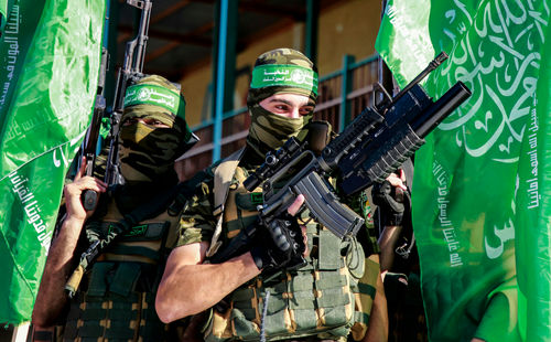 shutterstock_1979836574.jpg Two armed masked soldiers with green flags.