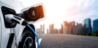 Electric car charging with city skyline background.