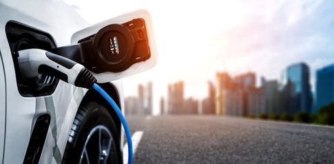 Electric car charging with city skyline background.