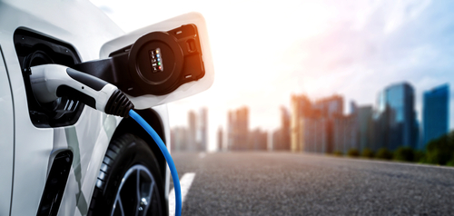 Electric car charging with city skyline background.