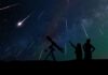 Silhouetted people stargazing with telescope under meteor shower.