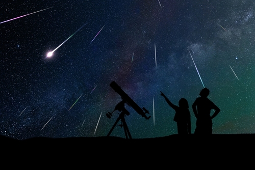 shutterstock_2096358130.jpg featured image Silhouetted people stargazing with telescope under meteor shower.