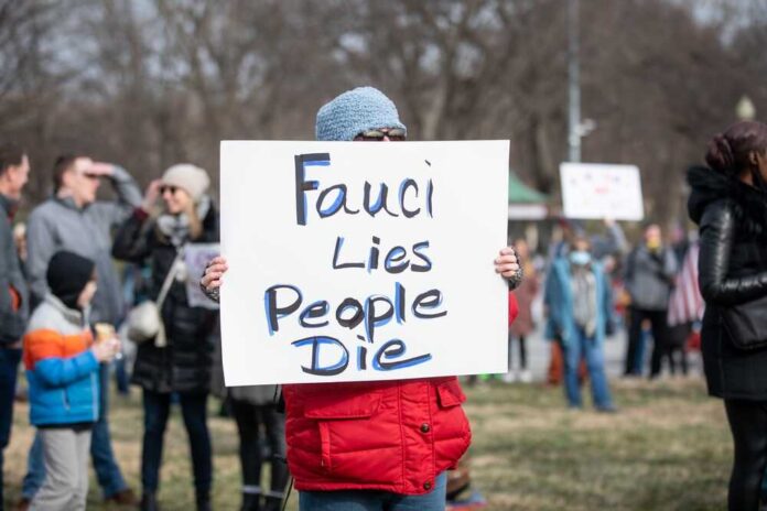 shutterstock_2115278627-1.jpg featured image Person holding sign that reads Fauci Lies People Die