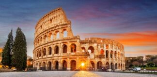 The Colosseum in Rome at sunset with a glowing sun in the background