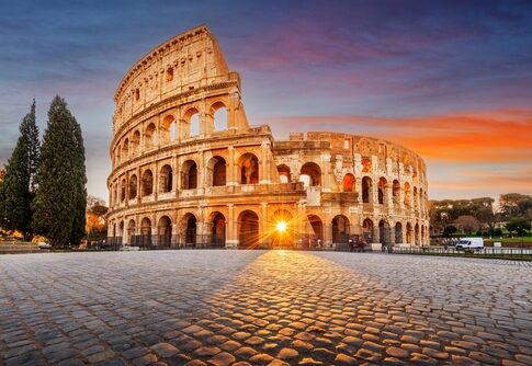 The Colosseum in Rome at sunset with a glowing sun in the background