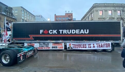 Truck with anti-Trudeau signage and protest banners in city.