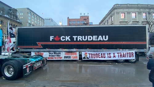 Truck with anti-Trudeau signage and protest banners in city.