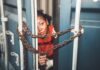 Person peeking through chained gap of a shipping container.