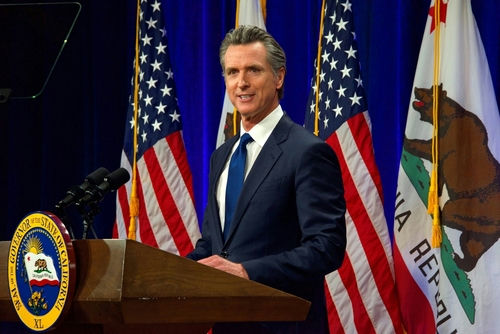 shutterstock_2137542759.jpg Governor Gavin Newsom speaks at podium with flags behind.