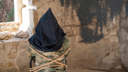 shutterstock_2139224883.jpg featured image Person hooded and bound in abandoned stone room.