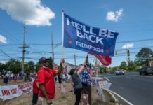 Pro-Trump supporters on street corner with 2024 flags.