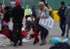People at an outdoor relief station with Red Cross supplies.