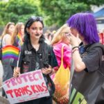 People at a pride event holding LGBTQ flags and signs.