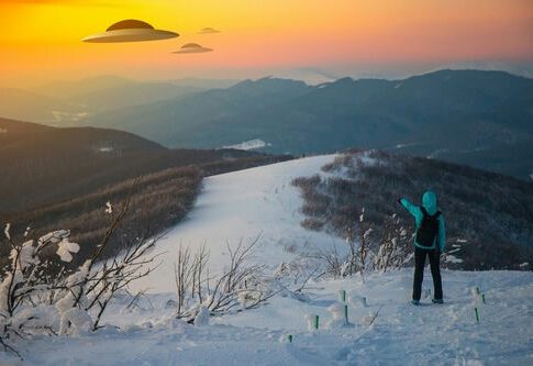 Person pointing at UFOs in snowy mountain landscape.