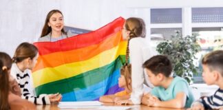 Teacher showing rainbow flag to children in classroom.