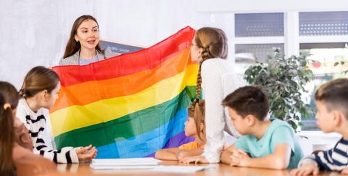 shutterstock_2264146151.jpg featured image Teacher showing rainbow flag to children in classroom.