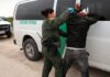 Border Patrol agent detains a man against a vehicle.