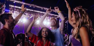 Group of people dancing and smiling at a concert.