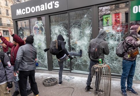 Protesters vandalizing a McDonald's restaurant with broken windows
