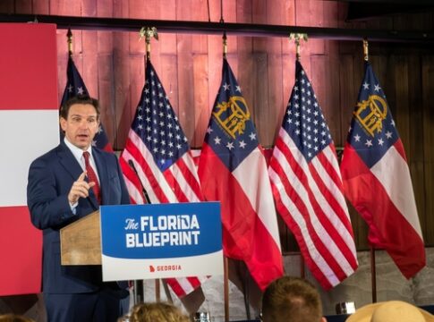 Man speaking at Florida Blueprint event with American flags.
