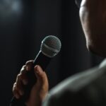 Person holding a microphone, speaking or singing.