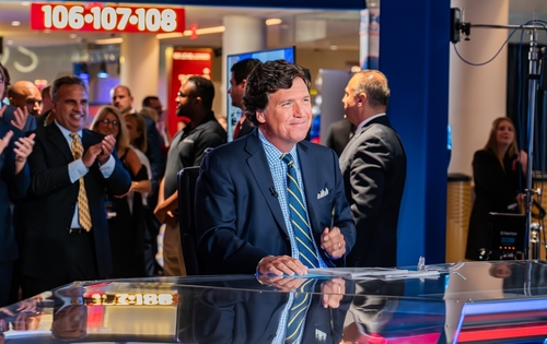 shutterstock_2359655319 (1).jpg featured image News anchor sitting at desk with people applauding.