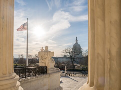 U.S. Capitol dome viewed between marble columns at sunset