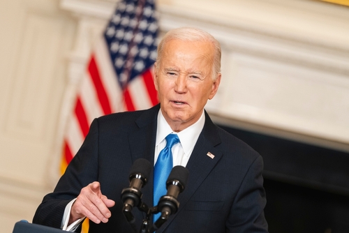 Man speaking at podium with American flag in background.