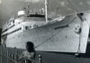 A large ship named docked at a pier.