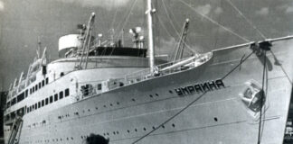 A large ship named docked at a pier.