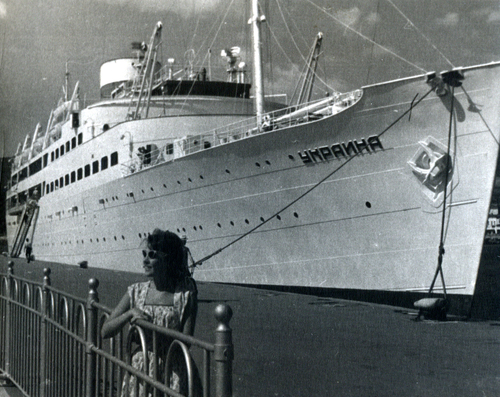 A large ship named docked at a pier.