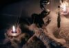 A dark, mystical scene featuring candles, a voodoo doll, and occult symbols